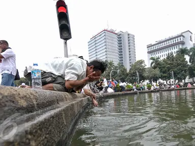 Seorang  demonstran memanfaatkan air kolam Bundaran Patung Kuda untuk wudhu salat Jumat, Jakarta, Jumat (4/11). Sebagian massa demonstan gelar salat Jumat di area Bundaran Patung Kuda. (Liputan6.com/Yoppy Renato)