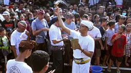 Seorang pemangku mencipratkan air pada peserta festival Omed-omedan di Bali, Kamis (29/3). Festival yang dilakukan sehari setelah Hari Raya Nyepi tersebut sekaligus untuk memohon keselamatan bagi warga setempat. (AP Photo/Firdia Lisnawati)