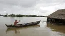 Seorang pria mendayung perahu mendekati sebuah rumah yang terendam banjir di Zalun Township, Irrawaddy Delta, Myanmar (6/8/2015). Meningkatnya volume luapan sungai sudah membahayakan warga sekitar di desa tersebut. (REUTERS/Soe Zeya Tun)