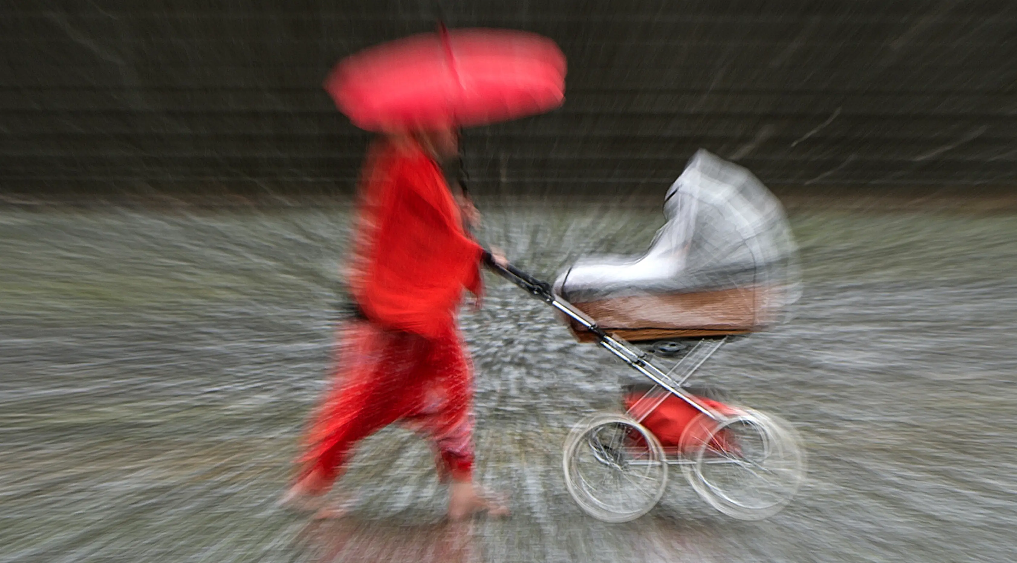 Seorang wanita berjalan selama hujan deras di Erfurt, Jerman, (29/6). Prakiraan cuaca memprediksi dalam beberapa hari Jerman dilanda hujan deras yang mengakibatkan banjir di beberapa titik ibu kota. (AP Photo / Jens Meyer)