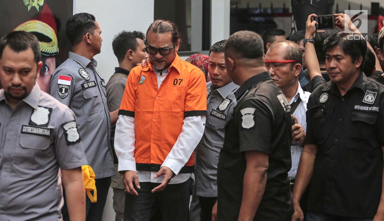 Suami komedian Tri Retno Prayudati alias Nunung, July Jan Sambiran digiring petugas saat dihadirkan dalam rilis kasus narkoba di Polda Metro Jaya, Jakarta, Senin (22/7/2019). July Jan Sambiran dan Nunung ditangkap usai bertransaksi narkoba. (Liputan6.com/Faizal Fanani)
