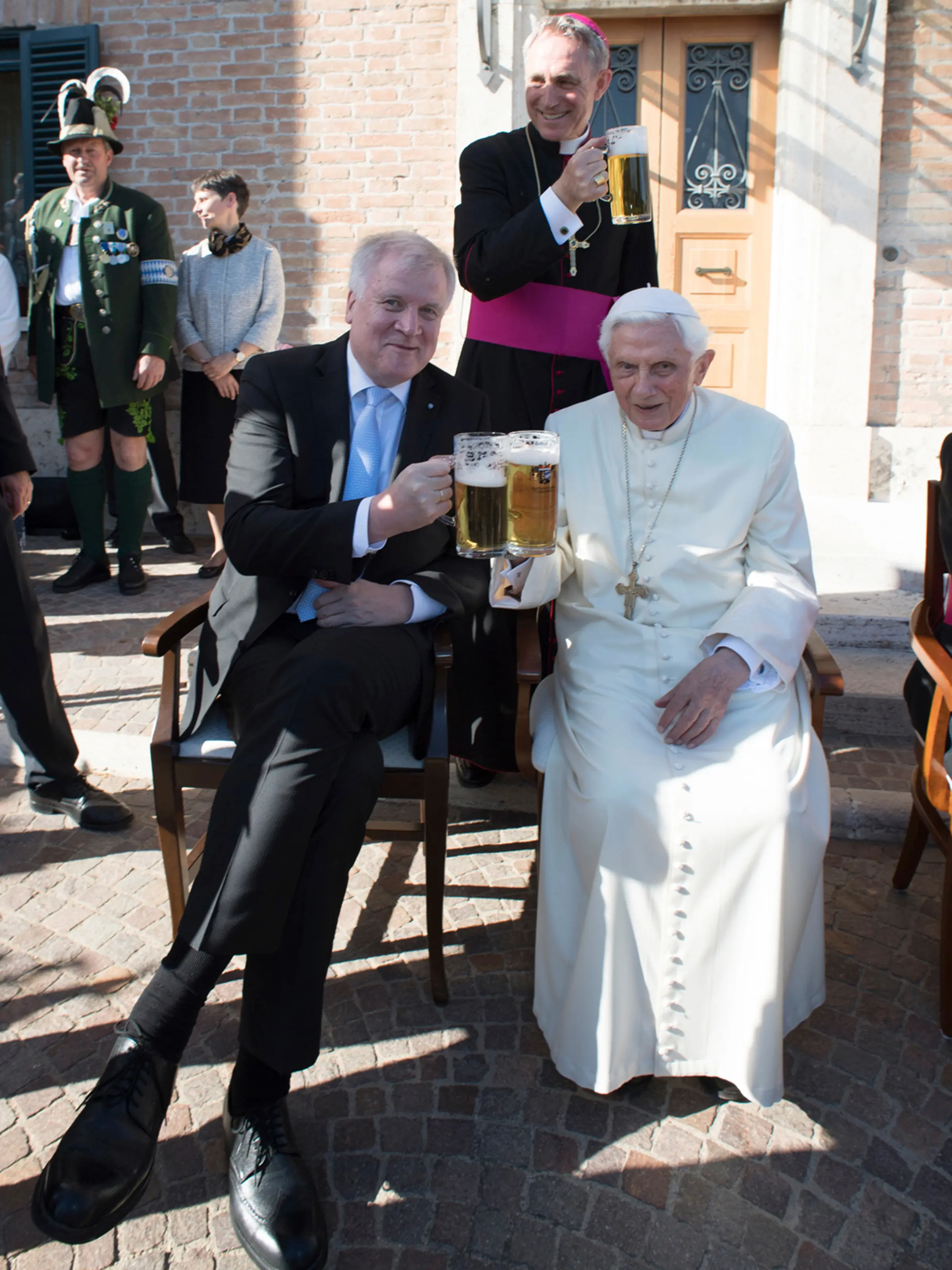 Paus Emeritus Benediktus XVI bersulang dengan dengan Perdana Menteri Bavaria Horst Seehofer saat merayakan ulang tahunnya yang ke-90 di Vatikan (17/4). (L'Osservatore Romano/Pool Photo via AP)