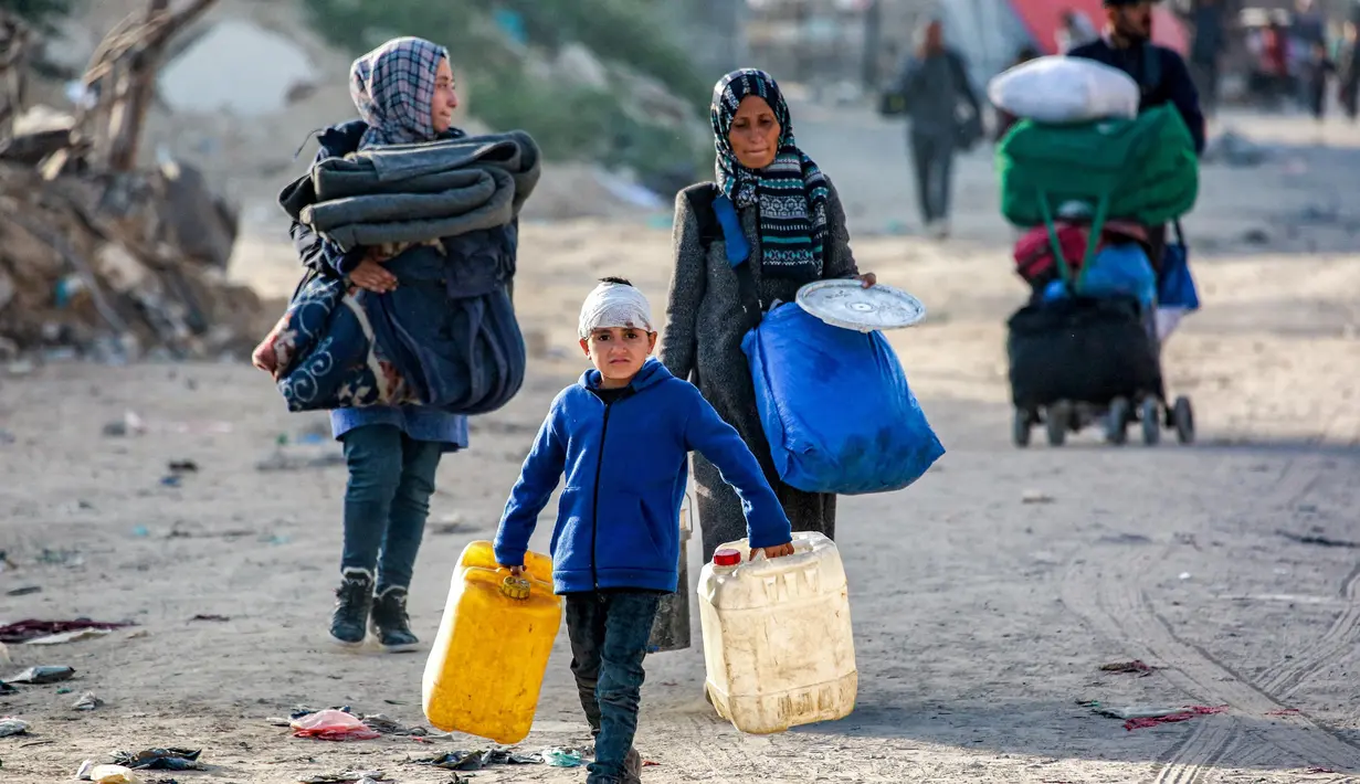 Seorang anak laki-laki berjalan dengan jeriken kosong bersama orang-orang yang mengungsi akibat konflik dan melarikan diri dari Beit Hanun, Jalur Gaza utara tiba di Kota Gaza pada 18 Maret 2025. (Bashar TALEB/AFP)