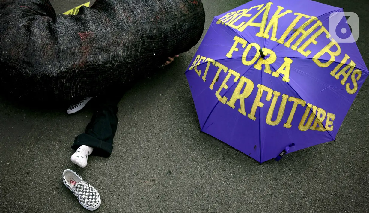 Seorang massa aksi berada di antara replika gurita raksasa oligarki saat aksi di Patung Kuda, Jakarta, Selasa (8/3/2022). Aksi tersebut untuk memperingati Hari Perempuan Internasional serta menuntut pengesahan RUU TPKS yang partisipatif dalam pembahasan dan pro korban. (Liputan6.com/Faizal Fanani)