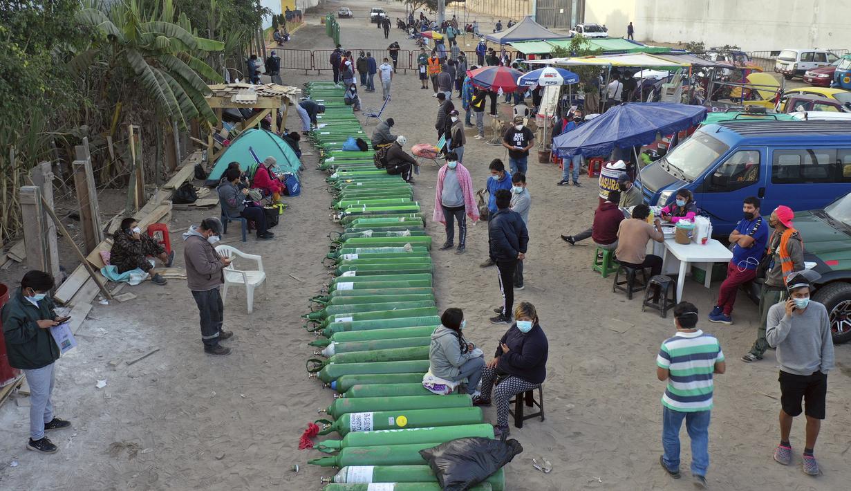 Lusinan tabung oksigen kosong tergeletak di jalan ketika orang-orang menunggu toko buka untuk mengisi tabung mereka di Villa El Salvador, Lima, Peru, Selasa (6/4/2021). Warga Peru terus berjuang mendapatkan oksigen medis untuk merawat pasien COVID-19. (AP Photo/Rodrigo Abd)