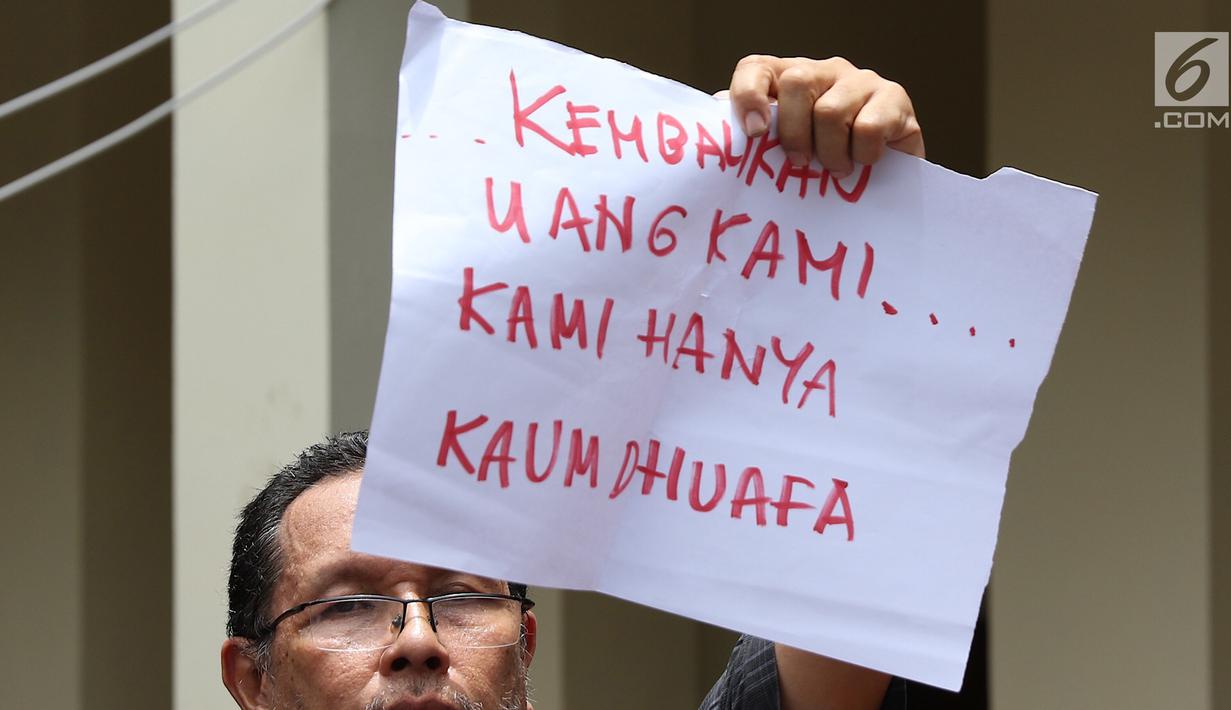 Seorang pria korban dugaan penipuan First Travel menunjukkan menunjukkan poster di Pengadilan Negeri Depok, Jawa Barat, Senin (19/2). Mereka diduga menipu calon jemaah dengan menawarkan perjalanan umrah dengan paket murah. (Liputan6.com/Immanuel Antonius)