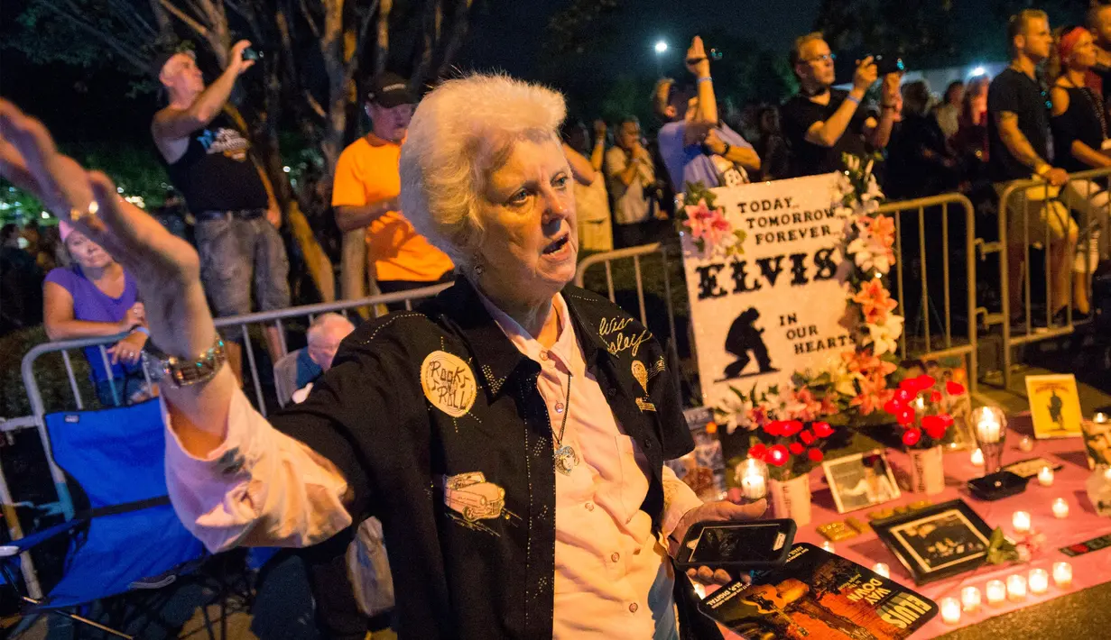 Salah seorang penggemar memutar lagu ‘American The Beautiful’ versi Elvis Presley pada peringatan 40 tahun kematian sang idola di Graceland, Memphis, Tenn, Selasa (16/8). (AP Photo/Brandon Dill)