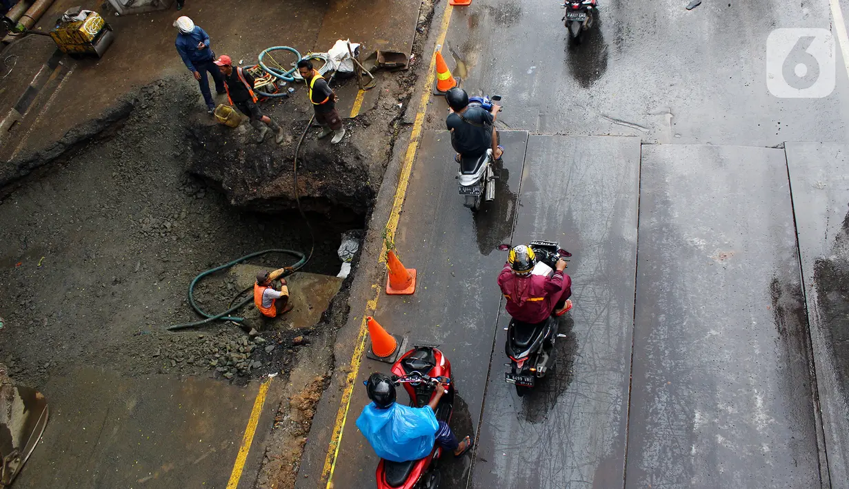 Pengendara melintas dekat perbaikan jalan ambles di Jalan Daan Mogot, Tangerang, Senin (13/1/2020). Amblesnya jalan penghubung ke Jakarta ini diduga karena adanya kebocoran pipa PDAM Tirta Kerta Raharja milik Pemkab Tangerang yang mengikis struktur tanah. (merdeka.com/Magang/Muhammad Fayyadh)