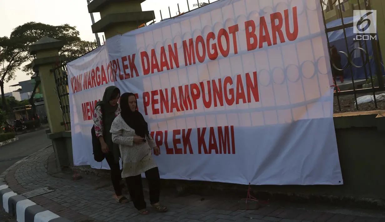 Pencari suaka melintasi spanduk penolakan di depan bekas Markas Kodim di Kalideres, Jakarta, Selasa (16/7/2019). Sejak Kamis (11/7) para pencari suaka dipindahkan dari di pinggir jalan dan trotoar di kawasan Kebon Sirih ke bekas Markas Kodim di Kalideres . (Liputan6.com/Helmi Fithriansyah)