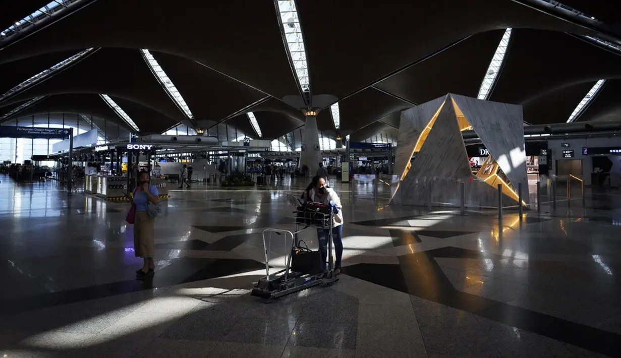 Pelancong mendorong barang bawaannya untuk check-in di Bandara Internasional Kuala Lumpur, Sepang, Malaysia, Jumat (1/4/2022). Mulai hari ini, Malaysia membuka perbatasannya untuk orang asing dan pelancong yang sudah divaksin COVID-19 lengkap tanpa harus menjalani karantina. (AP Photo/Vincent Thian)