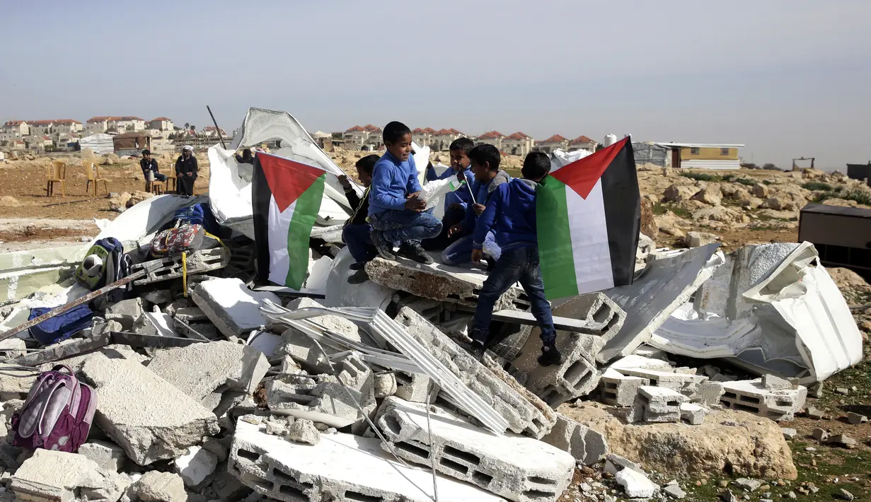 Anak-anak bermain di antara puing-puing sekolah mereka yang hancur di Desa Abu Nuwar, Tepi Barat, Palestina, Minggu (4/2). Israel menghancurkan sekolah mereka karena menganggap bangunan yang didanai Uni Eropa itu ilegal. (AP Photo/Mahmoud Illean)
