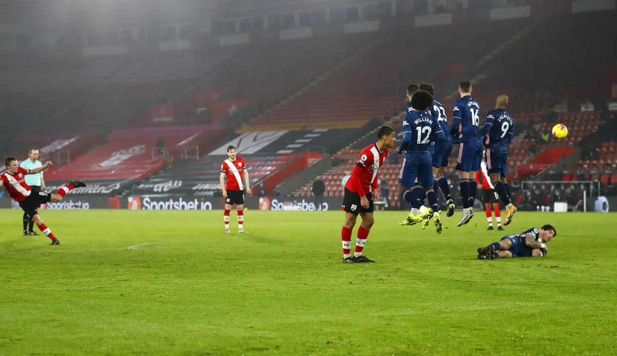 Pemain Arsenal Hector Bellerin berbaring di belakang tembok pertahanan saat rekan satu timnya melompat mengadang tendangan bebas pemain Southampton pada pertandingan Liga Inggris di Stadion St Mary, Southampton, Inggris, Selasa (26/1/2021). Arsenal menang 3-1. (AP Photo/Frank Augstein, Pool)