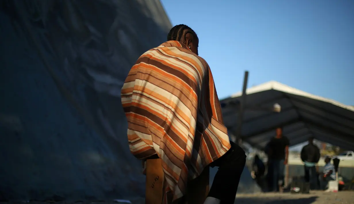 Seorang imigran Haiti menutupi tubuhnya dengan selimut di penampungan Padre Chava setelah meninggalkan Brasil, di Tijuana, Meksiko, Senin (3/10). Mereka pindah setelah gempa Haiti pada tahun 2010 dan memutuskan untuk pindah ke AS. (REUTERS/Edgard Garrido)