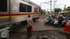 Sebuah kereta Commuter Line melintas di perlintasan kereta api Bintaro, Jakarta, Senin (16/1). Untuk mengurangi angka kecelakaan di perlintasan kereta api, Pemerintah Provinsi DKI Jakarta akan membangun jalan layang. (Liputan6.com/Gempur M. Surya)