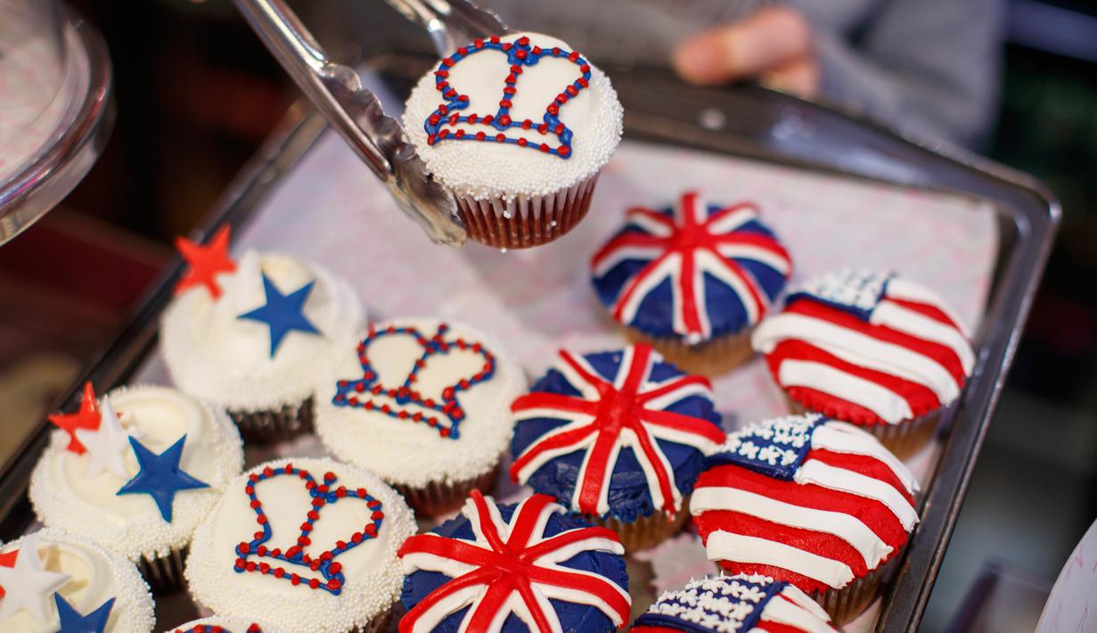 Karyawan memperlihatkan cupcakes edisi khusus untuk menghormati pernikahan Pangeran Harry dan Meghan Markle di Hummingbird Bakery, London, 11 Mei 2018. Pernikahan Harry dan Meghan digelar 19 Mei esok di Kapel St. George, Istana Windsor. (AFP/Tolga AKMEN)