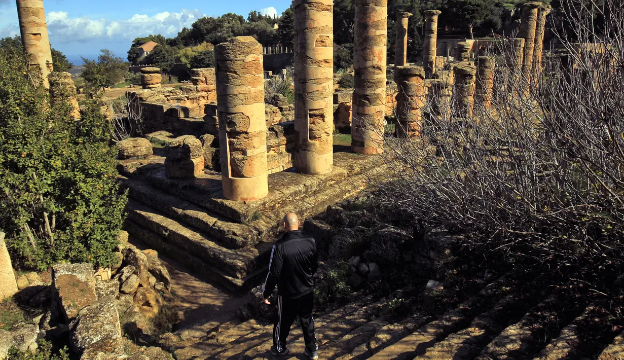 Seorang pria menuruni tangga di situs kota Yunani kuno Kirene di pinggiran kota Shehhat, Libya (13/12/2019). Kota tua Yunani ini menjadi bagian dari imperium yang dikuasai oleh Dinasti Ptolemeus dari Alexandria di Mesir dan jatuh ke tangan Kekaisaran Romawi.  (AFP/Abdullah Doma)