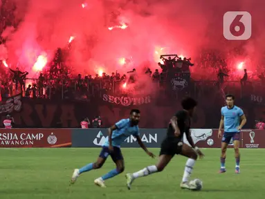 Suporter menyalakan flare saat menyaksikan laga Persija melawan Sabah FC pada laga uji coba internasional di Stadion Patriot Candrabhaga, Kota Bekasi, Minggu (5/6/2022). Pertandingan sepakbola kembali bisa disaksikan secara langsung setelah pemerintah melonggarkan aturan pemakaian masker di luar ruangan. (Liputan6.com/Helmi Fithriansyah)