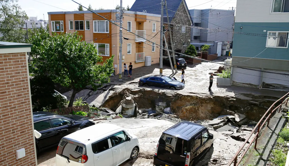 Sejumlah warga melihat kondisi jalan yang mengalami kerusakan parah akibat Gempa Magnitudo 6,7 di Sapporo, Hokkaido, Jepang, Kamis (6/9). (Hiroki Yamauchi/Kyodo News via AP)