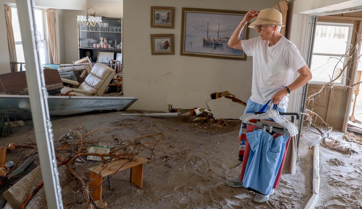Jody Wise menyelamatkan beberapa pakaian dari rumahnya yang penuh dengan lumpur pada tanggal 13 Oktober 2024 di Manasota Key, Florida, Amerika Serikat. (Joe Raedle/Getty Images North America/Getty Images via AFP)
