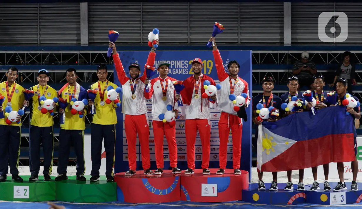 Tim voli pantai Indonesia melakukan selebrasi saat upacara pemberian medali pada voli pantai beregu putra SEA Games di Subic Court Tennis, Filipina, Jumat (6/12/2019). Indonesia berhasil meraih emas. (Bola.com/M Iqbal Ichsan)