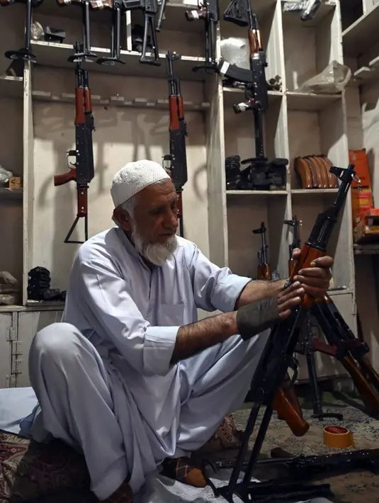 Seorang tukang senjata memperbaiki dan memoles senapan Kalashnikov di tokonya, Darra Adamkhel, Pakistan, 14 Desember 2022. Kota Darra Adamkhel telah lama dikenal dengan bazar pasar gelap senjatanya. (Abdul MAJEED/AFP)