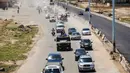 Mobil-mobil pemerintah dan kendaraan militer Rusia melintasi jalan raya utama antara Homs dan Hama yang dibuka kembali di Suriah, Rabu (6/6). Pembukaan kembali jalan raya itu menandai kemenangan untuk Presiden Suriah Bashar al-Assad. (AFP/STRINGER)