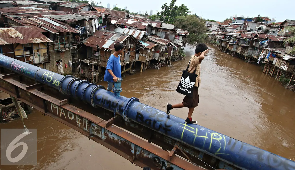 Warga menyebrangi bantaran Kali Ciliwung, Jakarta, Rabu (20/1). Apabila rusun yang disediakan telah siap ditempati Pemprov DKI Jakarta akan melakukan penggusuran pemukiman kumuh sebanyak mungkin. (Liputan6.com/Immanuel Antonius)