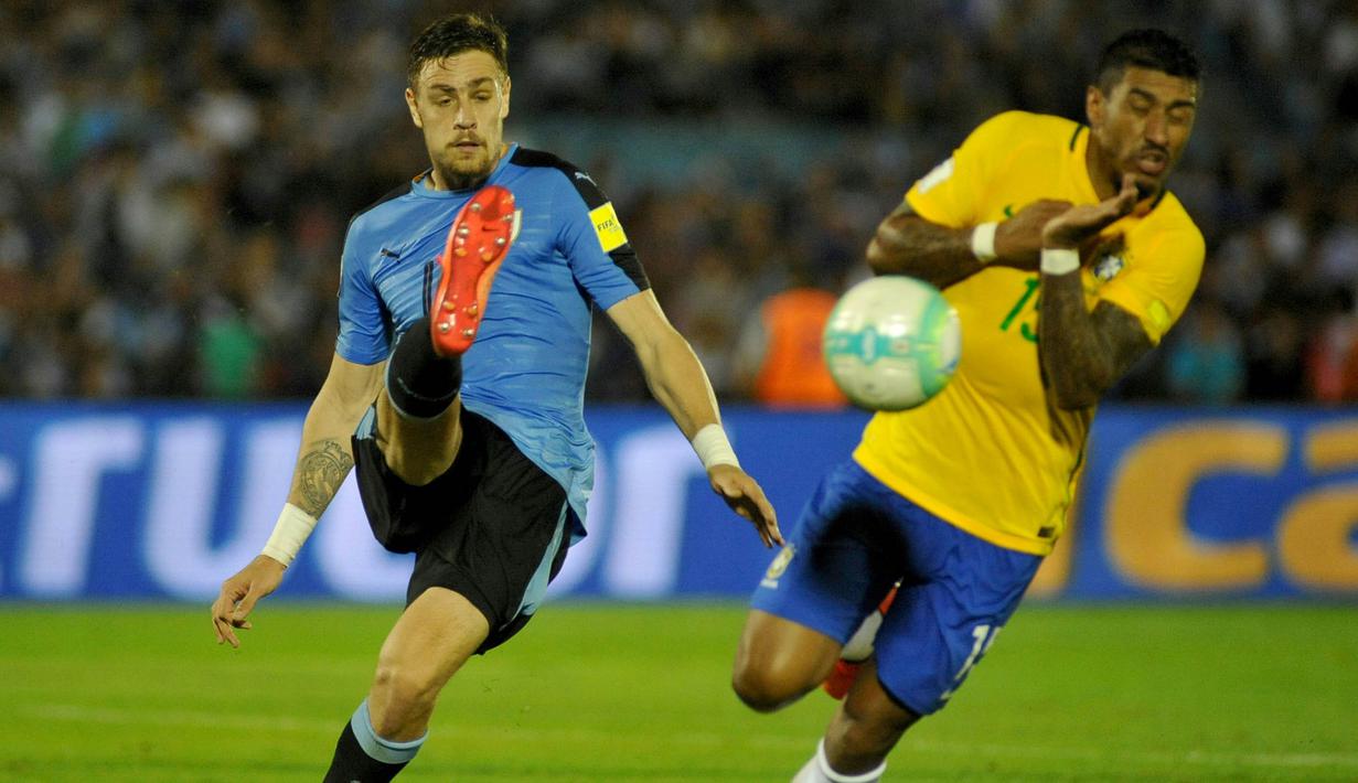 Gelandang Brazil, Paulinho, berusaha menghalau tendangan bek Uruguay, Sebastian Coates. Paulinho mencetak tiga gol dalam pertandingan tersebut. (AFP/ Dante Fernandes)
