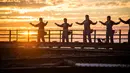 Praktisi Tai Chi melakukan latihan dengan latar belakang matahari terbenam di atas Jembatan Sydney Harbour, Australia, Selasa (2/5). Acara ini diselenggarakan oleh Akademi Tai Chi dan Qigong Australia. (Handout / BRIDGECLIMB SYDNEY / AFP)