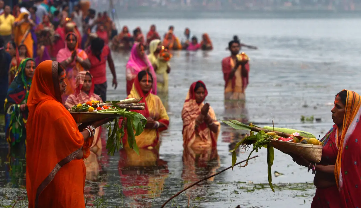 Umat Hindu India membawa sesajen ketika berdoa pada matahari di Kolkata saat Festival Chhath untuk memuja dewa matahari, Selasa (17/11). Dalam festival tersebut, sejumlah umat Hindu berdoa saat matahari terbit dan tenggelam. (AFP PHOTO/Dibyangshu SARKAR)