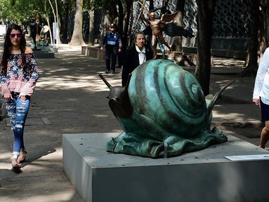 Pengunjung melihat patung "Snail dan Angel" saat pameran "Salvador Dali: Urban Dreams" di Mexico City, Selasa (14/3). Patung-patung tersebut adalah karya seniman asal spanyol yang bernama Salvador Dali. (AFP PHOTO / RONALDO SCHEMIDT)
