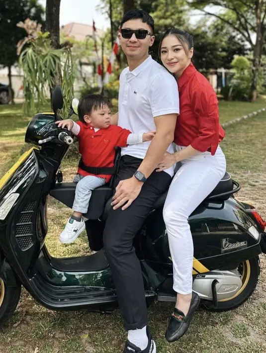 Nikita Willy mengenakan kemeja panjang merah, dipadukan celana putihnya. Kompak dengan baby Izz dan suami. [Instagram/@nikitawillyofficial94]