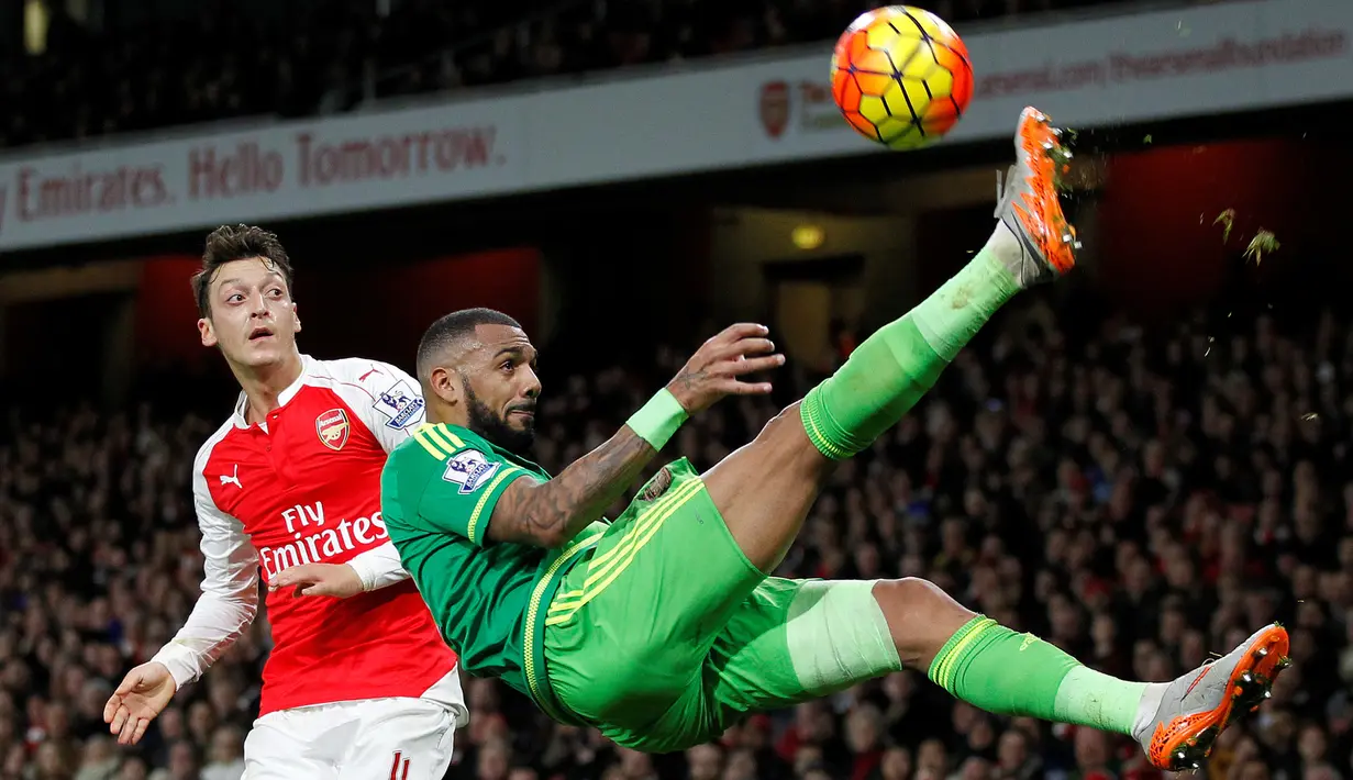 Pemain Arsenal, Mesut Ozil (kiri) melihat gelandang Sunderland, Yann M'vila, saat menendang salto dalam laga Liga Inggris di Stadion Emirates, London, (5/12/2015). (AFP/IKIMAGES/Ian Kington) 