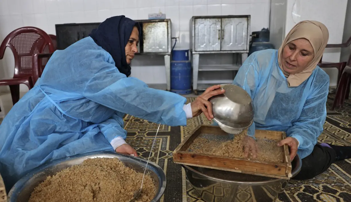 Para wanita membuat maftoul atau couscous di Khan Yunis, Jalur Gaza, Palestina, 10 Januari 2022. Maftoul dibentuk seperti granula-granula dan dikukus dalam mangkuk khusus. (SAID KHATIB/AFP)