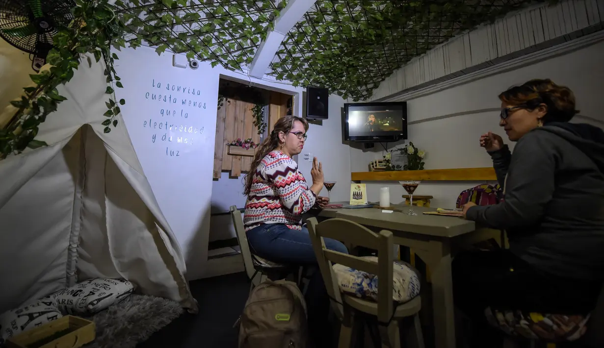 Pelanggan tunarungu berkomunikasi melalui bahasa isyarat di bar kopi "Sin Palabras" di Bogota (19/7).  Kafe ini merupakan kafe pertama di kota tersebut yang melayani para pengunjung tunarungu. (AFP Photo/Raul Arboleda)
