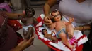 Isabel Anselmo (kiri) dan putrinya memegang tiga patung Bayi Yesus milik keluarga mereka setelah melakukan restorasi di Hospitalito de Ninos Dios Gaby atau Rumah Sakit Bayi Yesus Kecil Gaby dalam bahasa Spanyol di Mexico City, 28 Januari 2021. (AP Photo/Rebecca Blackwell)