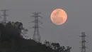 Bulan purnama muncul di balik menara tegangan tinggi El Avila di Caracas, Venezuela, Minggu (15/5/2022). Orang-orang di Amerika, Eropa, dan Afrika akan menyaksikan gerhana bulan total pada malam tanggal 15-16 Mei. (AP Photo/Matias Delacroix)