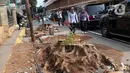 Pejalan kaki melintas di sisi sisa pohon yang ditebang untuk revitalisasi trotoar di kawasan Cikini, Jakarta, Kamis (21/11/2019). Setiap 21 November diperingati sebagai Hari Pohon Sedunia, hal ini untuk mengingatkan masyarakat akan manfaat tanaman bagi kehidupan. (Liputan6.com/Helmi Fithriansyah)
