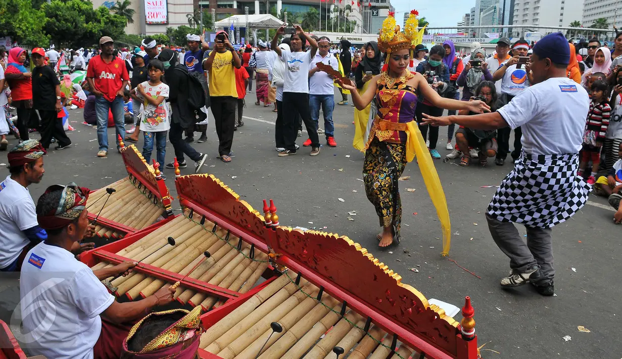 Seorang peserta ikut menari Tari Pendet khas Bali dalam parade kebudayaan bertajuk 'Kita Indonesia' di kawasan Bundaran HI, Jakarta, Minggu (4/12). Para peserta Parade Kebudayaan tampak antusias menyaksikan tarian itu. (Liputan6.com/Angga Yuniar)