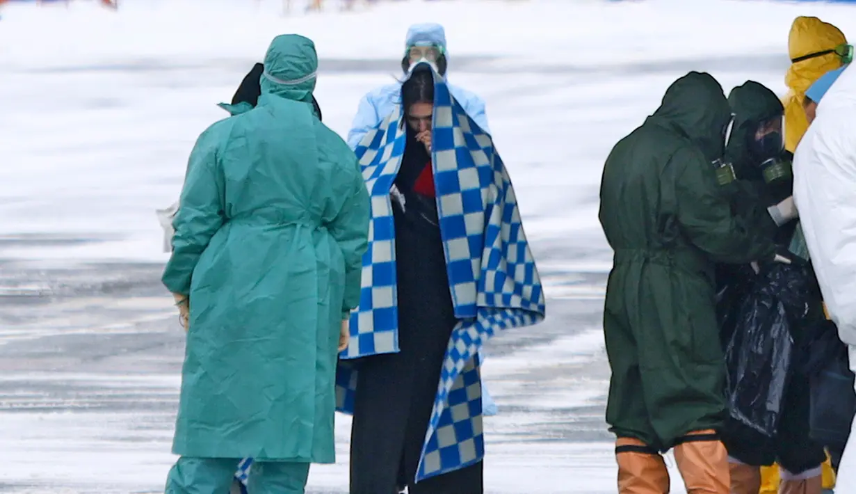 Petugas medis menyambut kedatangan warga yang turun dari pesawat militer di sebuah bandara luar Tyumen, Rusia, Rabu (5/2/2020). Seluruh warga yang dievakuasi dari Wuhan menyusul wabah virus corona tersebut akan dikarantina selama dua minggu di Siberia. (AP Photo/Maxim Slutsky)
