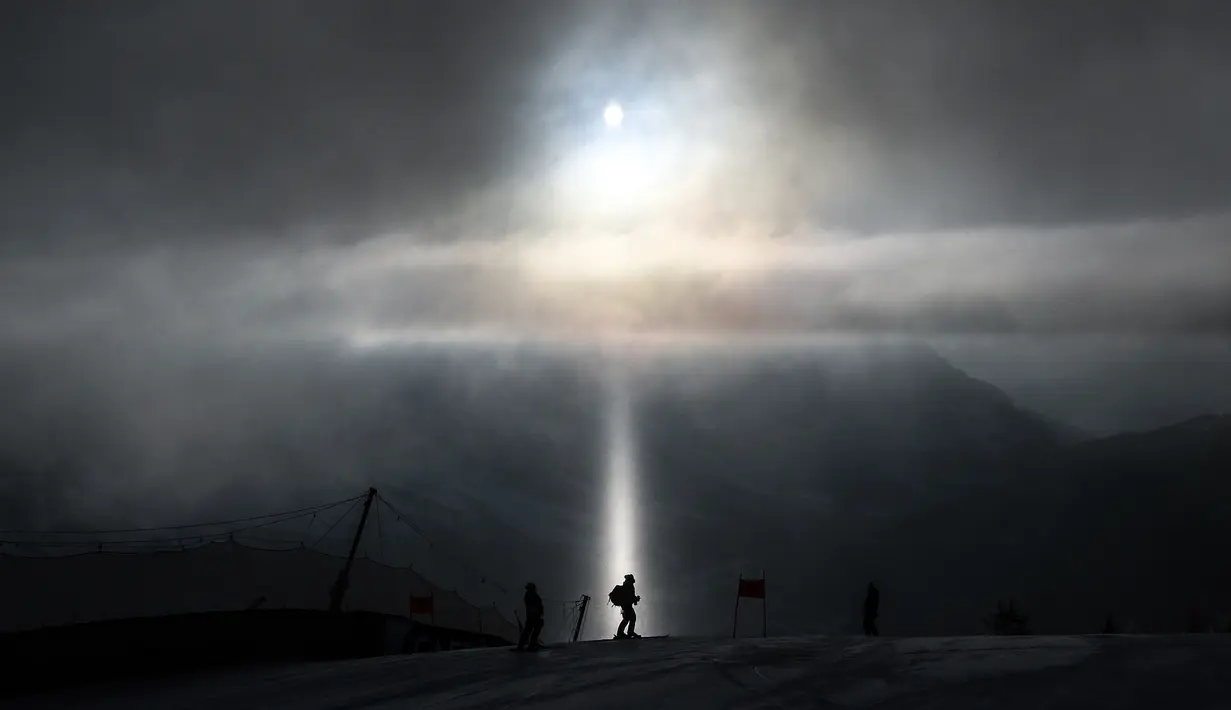Pelatih berjalan melintasi sinar cahaya, saat melakukan pemeriksaan jalur ski dalam Kejuaraan FIS Alpine World Ski. (Foto: AFP/Fabrice Coffrini)