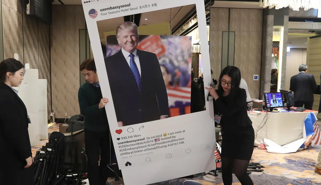 Kardus bergambar Donald Trump diangkat petugas saat menonton siaran langsung pemilihan presiden AS yang digelar di Kedutaan Besar Seoul, Korea Selatan, Rabu (9/11). (AP Photo / Lee Jin-man)