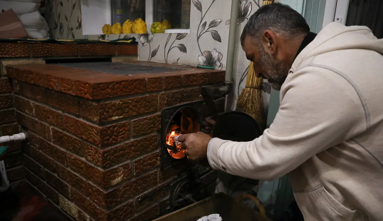 Gheorghe Batca memasukkan kayu bakar ke kompor yang memanaskan rumahnya di luar Chisinau, Moldova, 16 Oktober 2022. Krisis energi yang melanda Eropa karena dipicu pemotongan aliran gas alam oleh Rusia di tengah perangnya melawan Ukraina telah memaksa beberapa orang untuk beralih ke kayu bakar untuk menghangatkan diri dalam cuaca yang beranjak dingin. (AP Photo/Aurel Obreja)