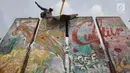 Pekerja memasang bongkahan Tembok Berlin dan Patung Menembus Batas di RPTRA Kalijodo, Jakarta, Selasa (26/9). Empat segmen pecahan Tembok Berlin dan 14 "Patung Menembus Batas" untuk memperindah bekas lokalisasi Kalijodo. (Liputan6.com/Immanuel Antonius)