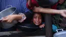 Seorang anak perempuan Palestina menunggu dalam antrean untuk menerima makanan di luar pusat distribusi di selatan Khan Yunis pada 6 Desember 2024. (BASHAR TALEB/AFP)