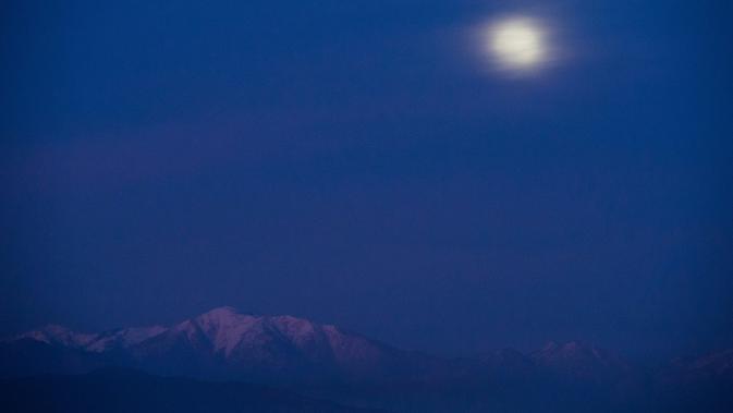 Fenomena gerhana bulan total atau supermoon yang sebagaian tertutup awan terlihat di atas Hutan Nasional Angeles, Los Angeles, Minggu (20/1). Supermoon terlihat dari sejumlah wilayah Amerika Utara dan Selatan, Eropa, dan Afrika Barat. (Robyn Beck / AFP)