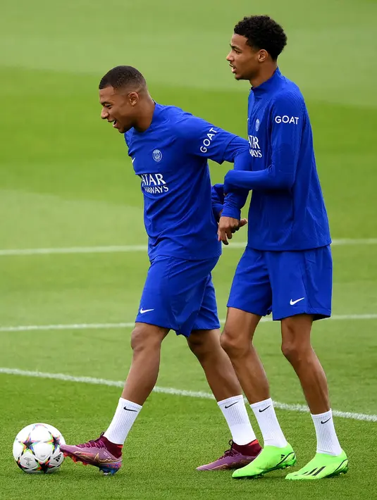 Pemain Paris Saint-Germain Kylian Mbappe (kiri) tertawa bersama Hugo Ekitike saat sesi latihan di tempat latihan klub di Saint-Germain-en-Laye, Prancis, Selasa (13/9/2022). Paris Saint-Germain (PSG) akan melawan Maccabi Haifa pada pertandingan sepak bola putaran pertama Grup H Liga Champions. (FRANCK FIFE/AFP)