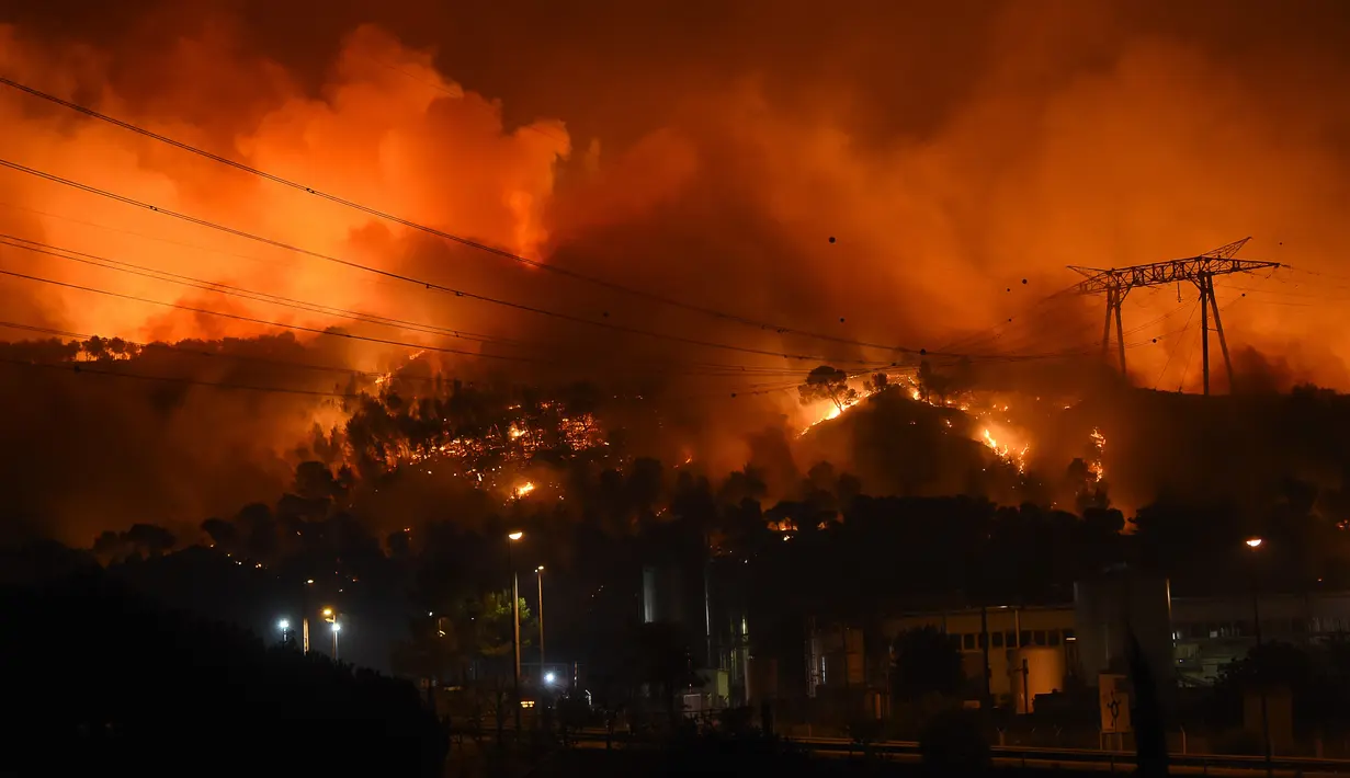 Kobaran api terlihat melahap lahan hutan dan rumah penduduk di Les Pennes-Mirabeau, Marseille, Prancis, (11/8). Kebakaran menghanguskan 2.260 hektare lahan hutan dan ratusan bangunan warga. (AFP PHOTO/BORIS HORVAT)