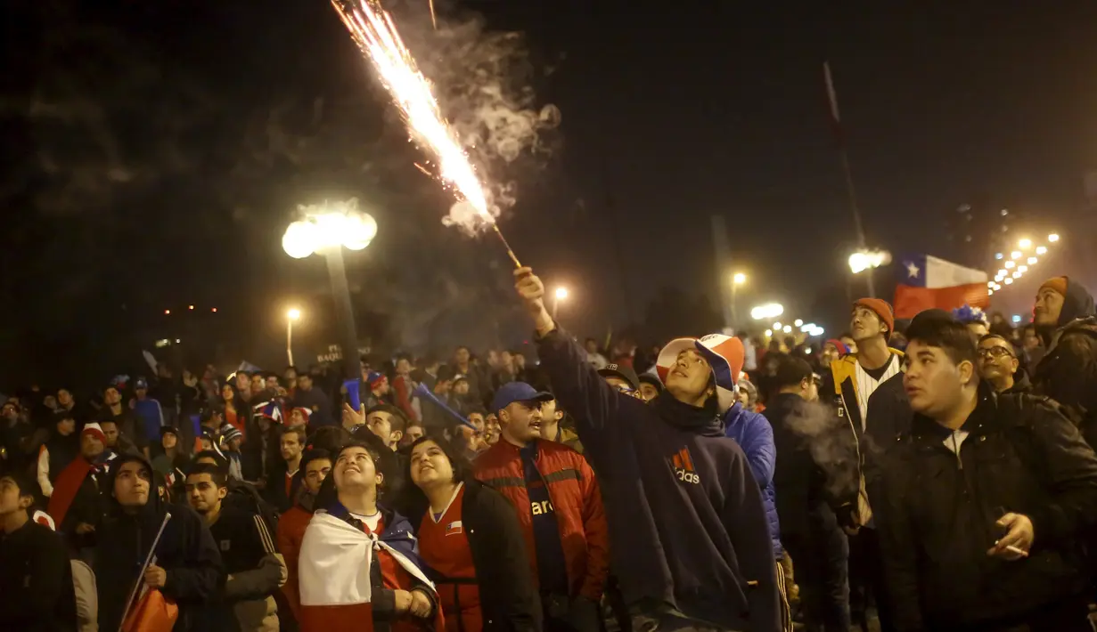 Seorang Suporter menyalakan kembang api merayakan kemenangan Chile atas Uruguay di Copa America 2015 di Santiago, Chile, (25/6/2015). Chile melaju ke semifinal usai mengalahkan Uruguay 1-0. (REUTERS/Pablo Sanhueza)