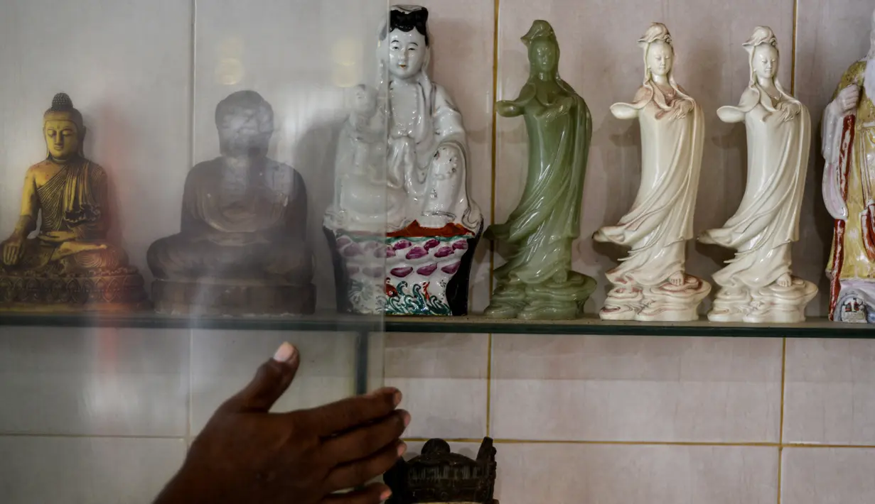 Seorang pria saat membersihkan patung dewa dan dewi di sebuah kuil China menjelang Tahun Baru Imlek di Banda Aceh (19/1/2020). Tahun Baru Imlek jatuh pada 25 Januari tahun ini dan menandai Tahun Tikus. (AFP Photo/Chaideer Mahyuddin)